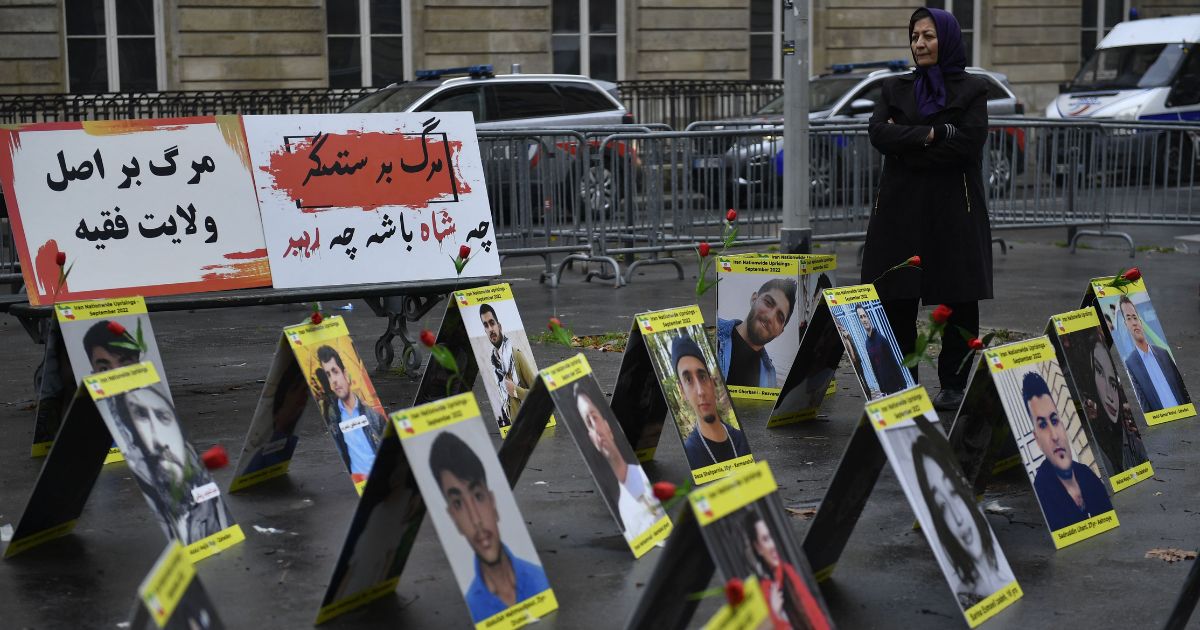 A woman protesting for Iranians Paris, France, stands next to placards with portraits of victims of Iran's repression on Tuesday.