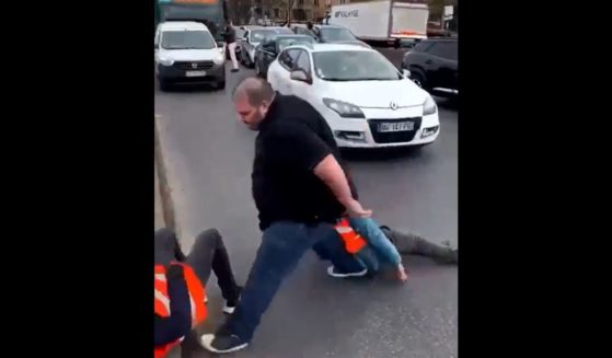 A man drags climate activists who were blocking a road near Paris.