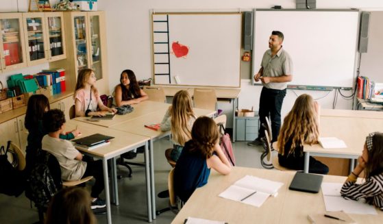 A stock photo shows a male instructor teaching middle school students.