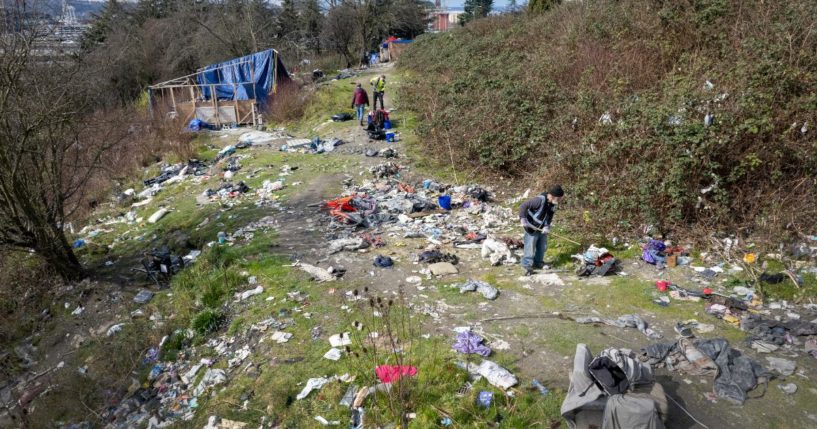 A group of people collect garbage surrounding a homeless encampment in Seattle, Washington, on March 12.