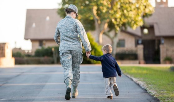 A service member walks alongside her child.