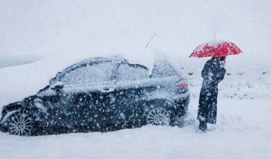 This stock photo shows a woman stranded on the side of the road in a snowstorm.
