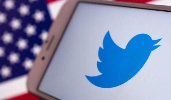 A cellphone displays the Twitter logo in front of an American flag in the above stock image.