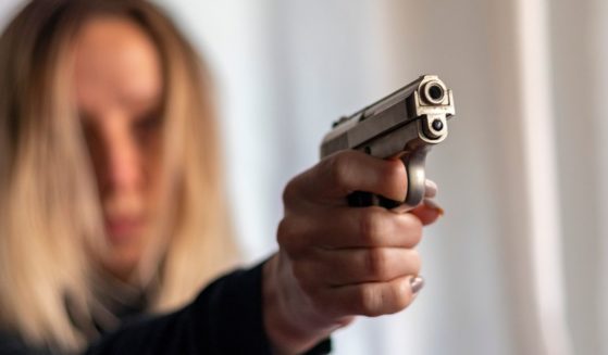 A woman holds up a gun in self-defense.