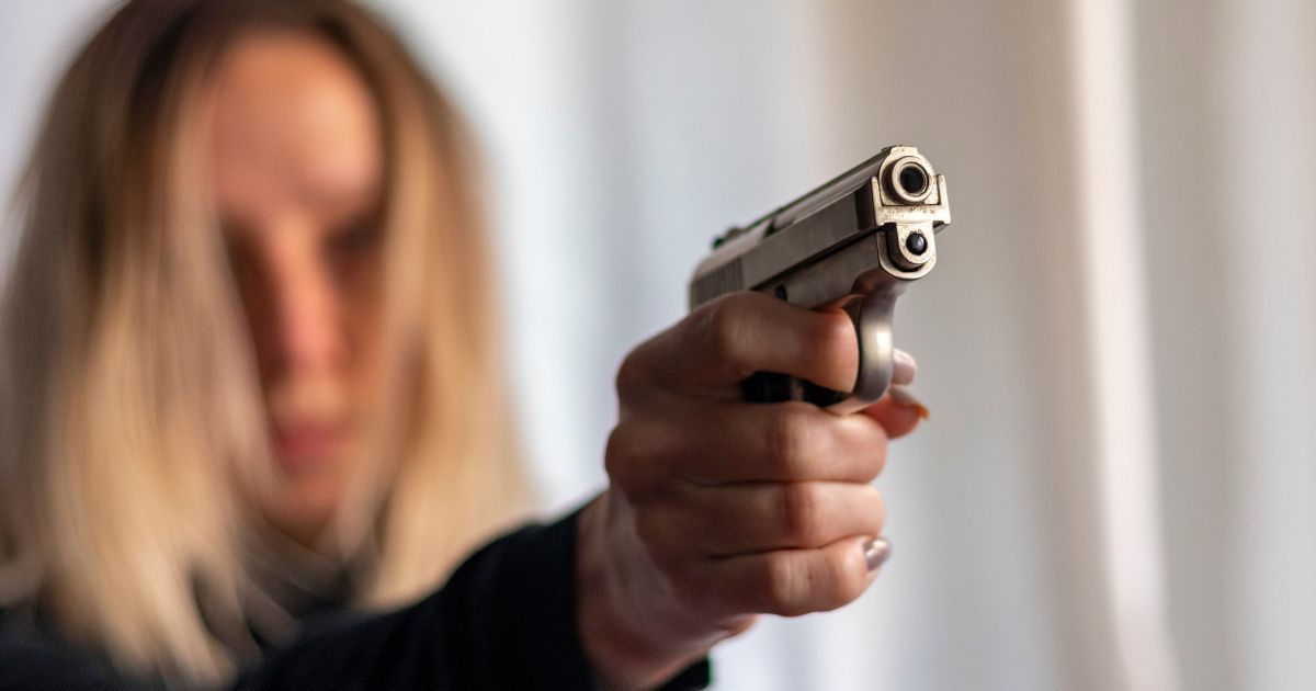 A woman holds up a gun in self-defense.