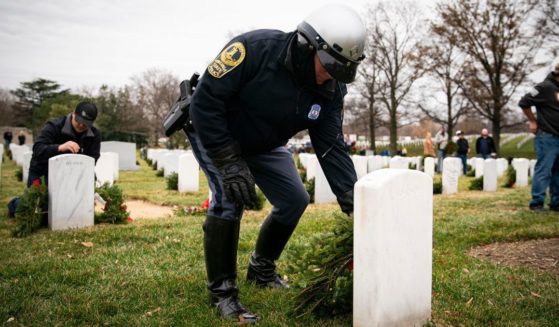 A Virginia state trooper places a wreath at a tombstone in Arlington National Cemetery as a part of the Wreaths Across America project, which places wreaths on over 250,000 military tombstones in Arlington.