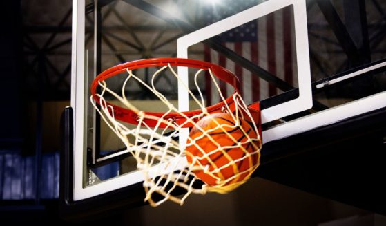 A basketball goes through the hoop in the above stock image.