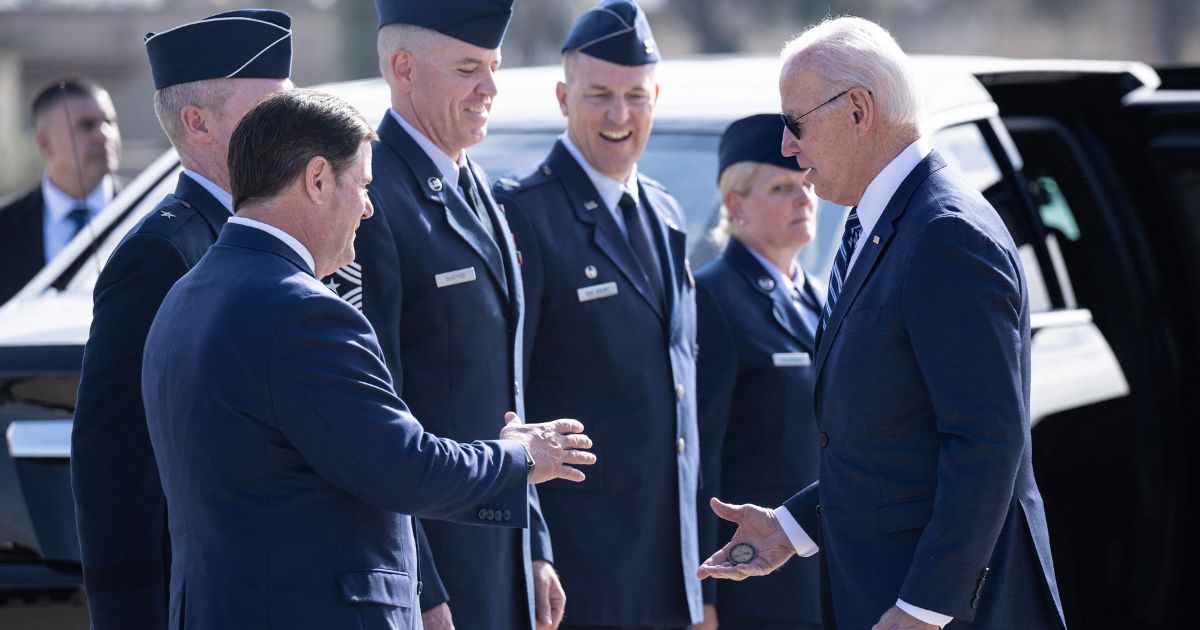 President Joe Biden hands a challenge coin to Arizona Governor Doug Ducey after disembarking from Air Force One at Luke Air Force Base in Glendale, Arizona, on Dec. 6.