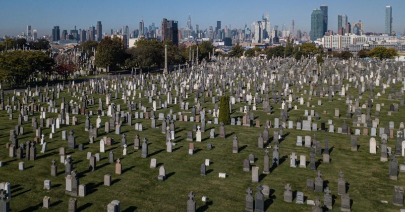 An aerial general view shows grave stones of the Cavalry cemetery in Queens, before the city skyline of Manhattan, on October 22, 2022 in New York.