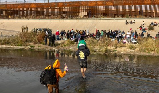 Immigrants wade across the Rio Grande at a high-traffic illegal border crossing area into El Paso, Texas on Dec. 20. Texas Governor Greg Abbott ordered 400 Texas National Guard troops to the U.S.-Mexico border in El Paso, which is under a state of emergency due to a surge of migrants crossing from Mexico into the city. Border officials expect an even larger migrant surge at the border if the pandemic era Title 42 regulation is lifted.