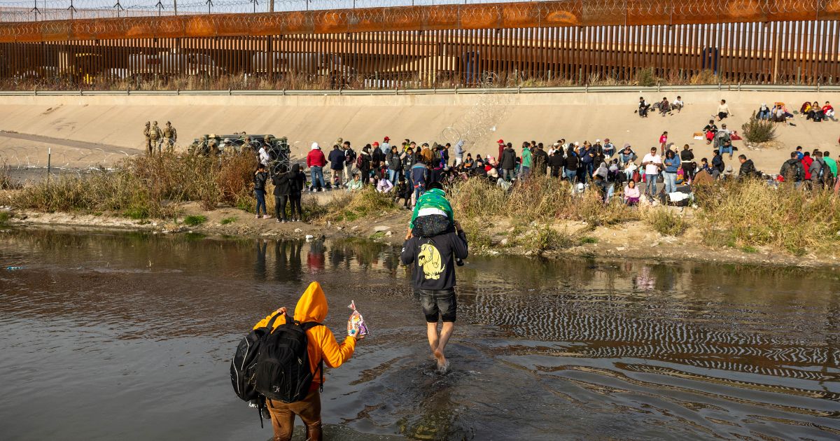 Immigrants wade across the Rio Grande at a high-traffic illegal border crossing area into El Paso, Texas on Dec. 20. Texas Governor Greg Abbott ordered 400 Texas National Guard troops to the U.S.-Mexico border in El Paso, which is under a state of emergency due to a surge of migrants crossing from Mexico into the city. Border officials expect an even larger migrant surge at the border if the pandemic era Title 42 regulation is lifted.