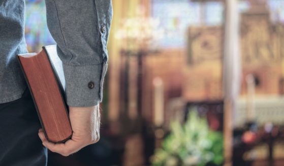 A man holds a Bible in a church in the above stock image.