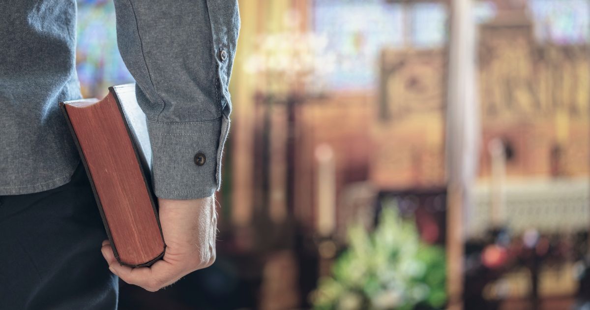 A man holds a Bible in a church in the above stock image.