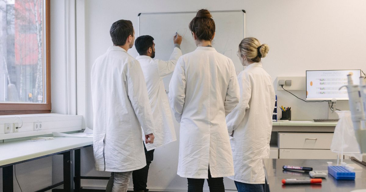 Medical students gather around a whiteboard in this stock image.