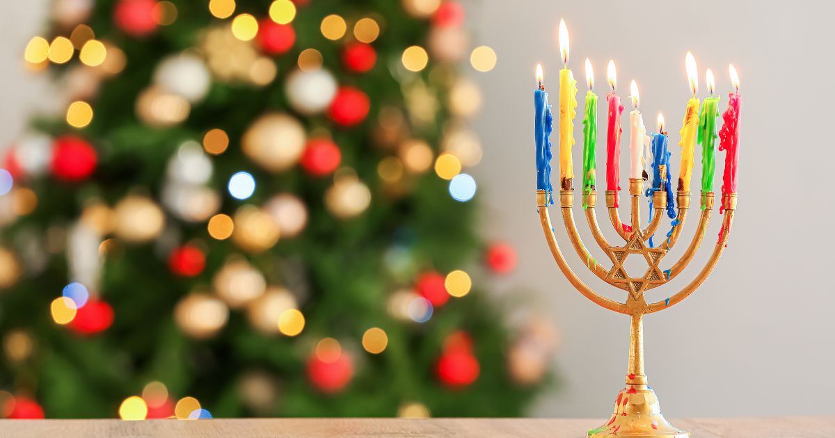 A menorah stands in front of a Christmas tree in the above stock image.