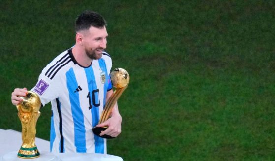 Argentina's Lionel Messi, holding the Golden Ball award for best player of the tournament, caresses the World Cup trophy at the end of the World Cup final soccer match between Argentina and France at the Lusail Stadium in Lusail, Qatar, on Sunday.