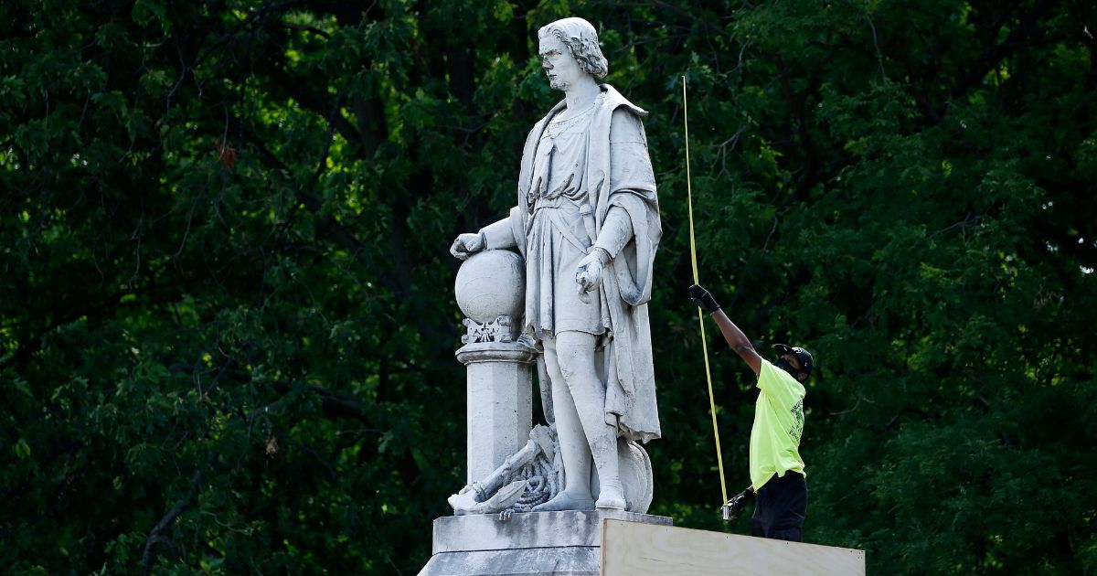 A city worker measures the statue of Christopher Columbus at Marconi Plaza in Philadelphia June 16, 2020.