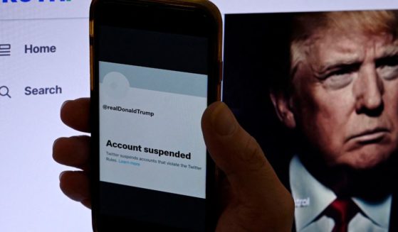 In this photo illustration, the suspended Twitter account of former US President Donald Trump is displayed on a mobile phone with former President Trump's Truth's page shown in the background.