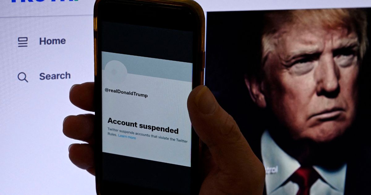 In this photo illustration, the suspended Twitter account of former US President Donald Trump is displayed on a mobile phone with former President Trump's Truth's page shown in the background.
