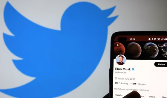 The Twitter account of Elon Musk is displayed on a smartphone with a Twitter logo in the background on November 21, 2022 in Newcastle Under Lyme, England.