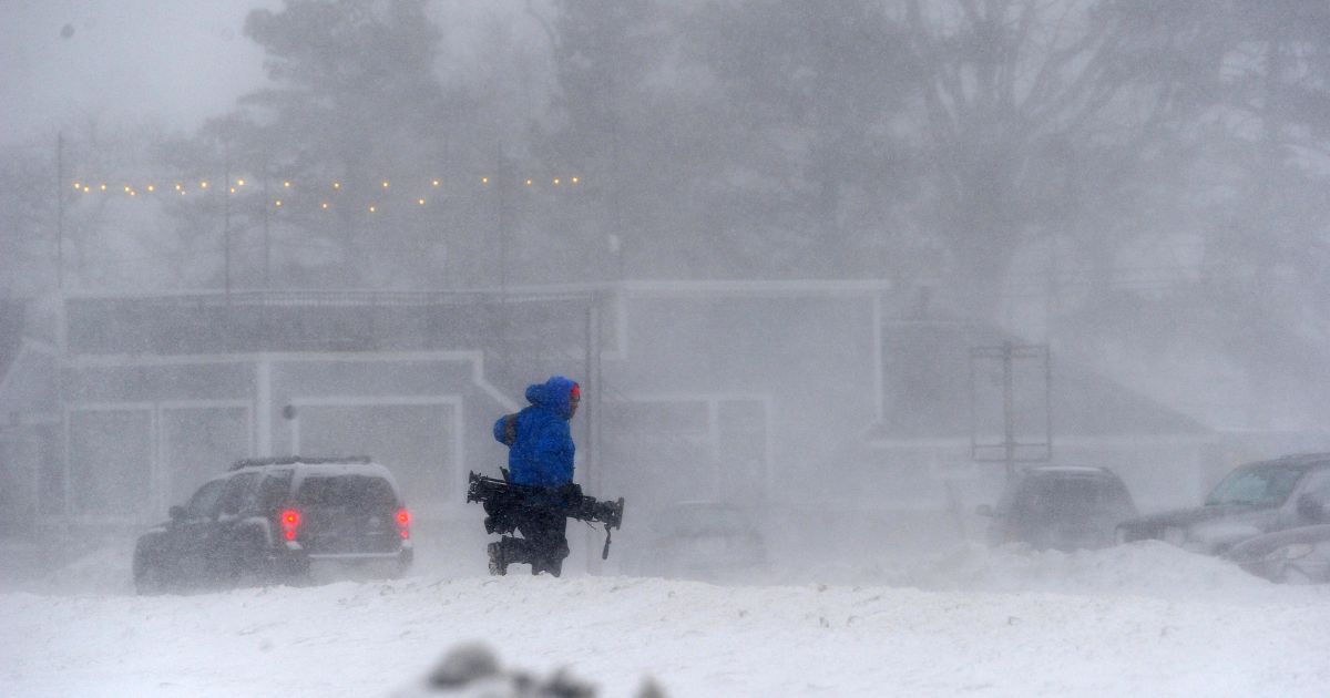 A member of the media battles snow and ice as Lake Erie waters wash over the shoreline on December 23, 2022 in Hamburg, New York.