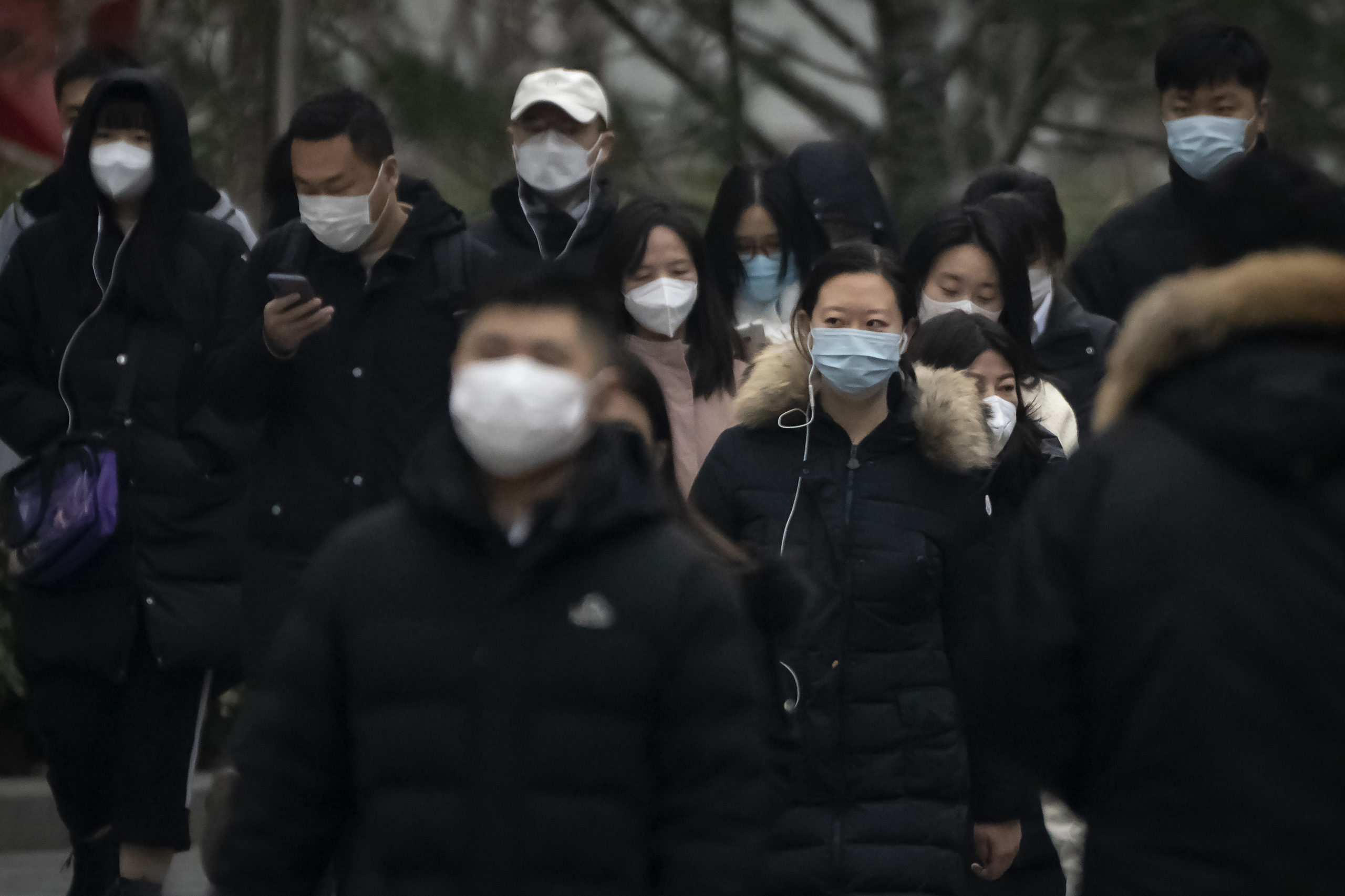 Commuters wearing masks walk along a street in the central business district in Beijing Thursday.