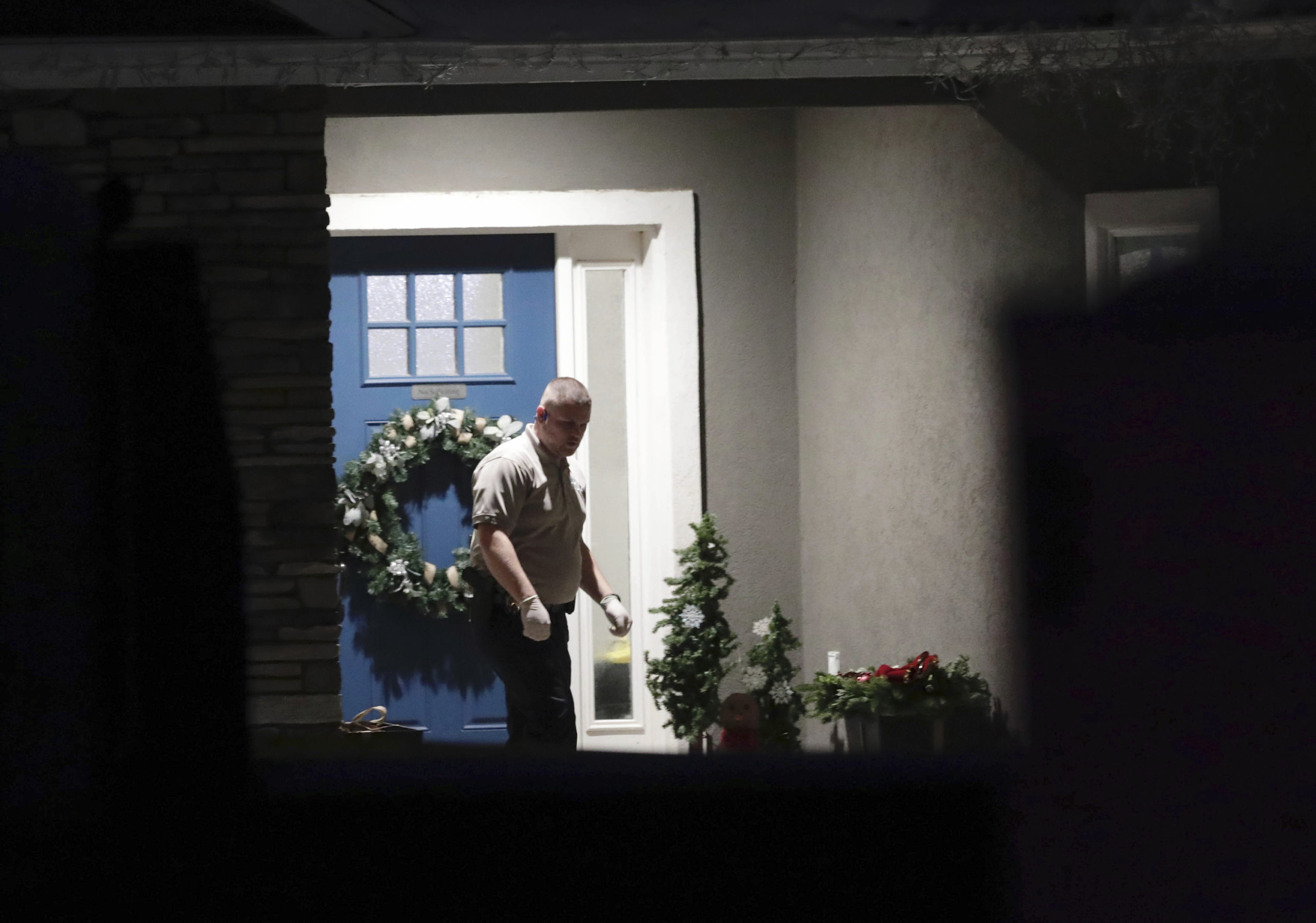 A law enforcement official stands near the front door of the Enoch, Utah, home where eight family members were found dead from gunshot wounds on Wednesday.