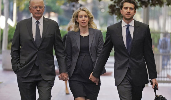 Former Theranos CEO Elizabeth Holmes arrives at federal court in San Jose, California, on Oct. 17 with her father, Christian Holmes IV, left, and her partner, Billy Evans.