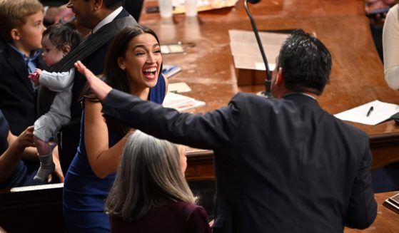 Rep. Alexandria Ocasio-Cortez laughs with a fellow lawmaker.