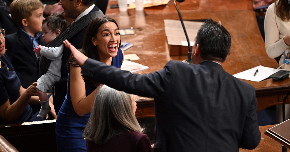 Rep. Alexandria Ocasio-Cortez laughs with a fellow lawmaker.