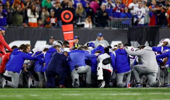 Buffalo Bills players and staff kneel together after teammate Damar Hamlin sustained a serious injury in the first quarter against the Cincinnati Bengals at Paycor Stadium on Monday night.