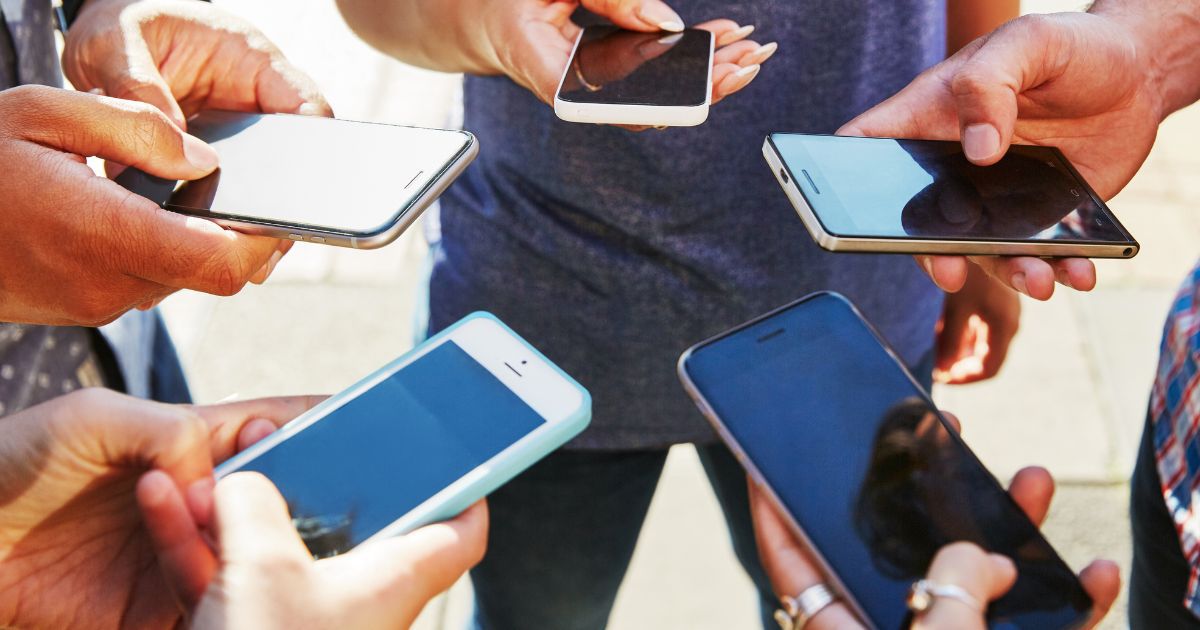 This stock photo shows a group of people checking their smartphones.