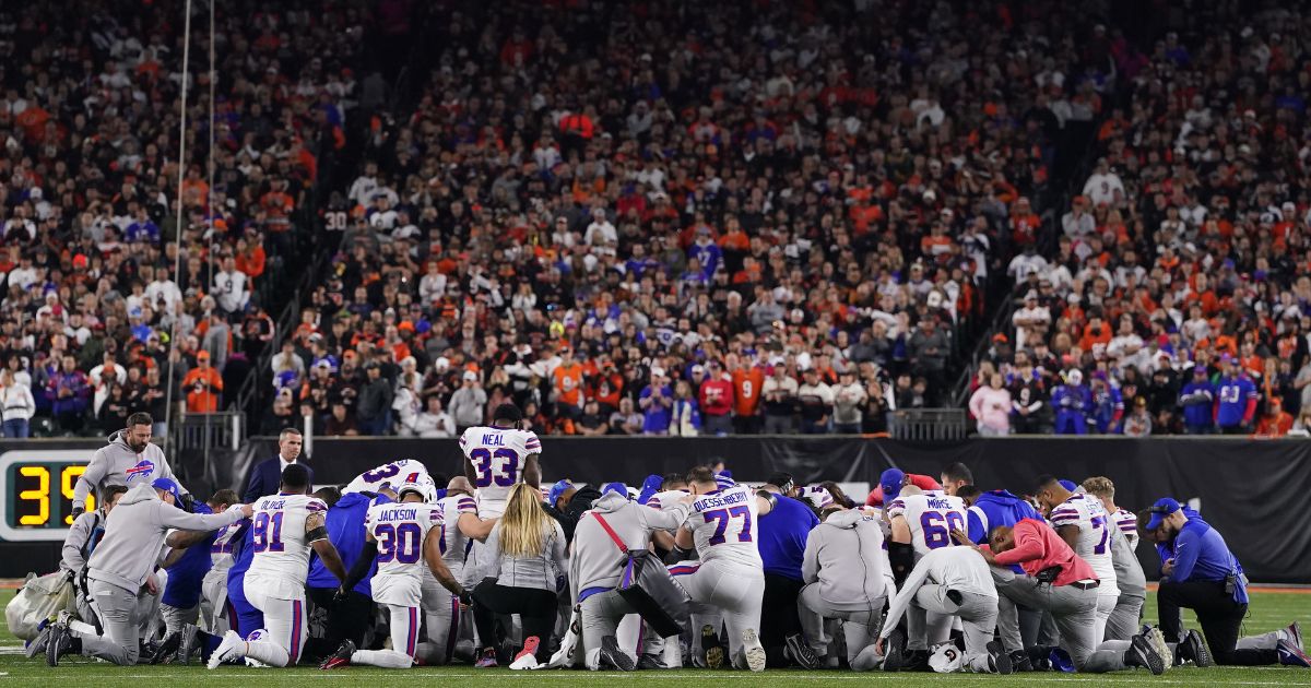 Buffalo Bills players huddle and pray after teammate Damar Hamlin collapsed on the field during the first quarter of a game against the Cincinnati Bengals at Paycor Stadium on Jan. 2 in Cincinnati, Ohio.