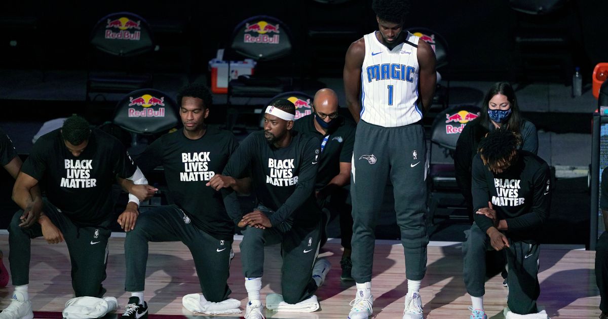 Jonathan Isaac of the Orlando Magic stands as others kneel before the team's game against the Brooklyn Nets at the ESPN Wide World of Sports Complex in Lake Buena Vista, Florida, on July 31, 2020.