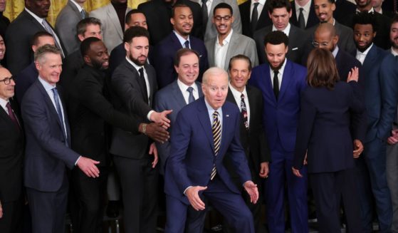 President Joe Biden jokes after posing for a photo with the Golden State Warriors during a ceremony honoring the team in the East Room of the White House Tuesday.