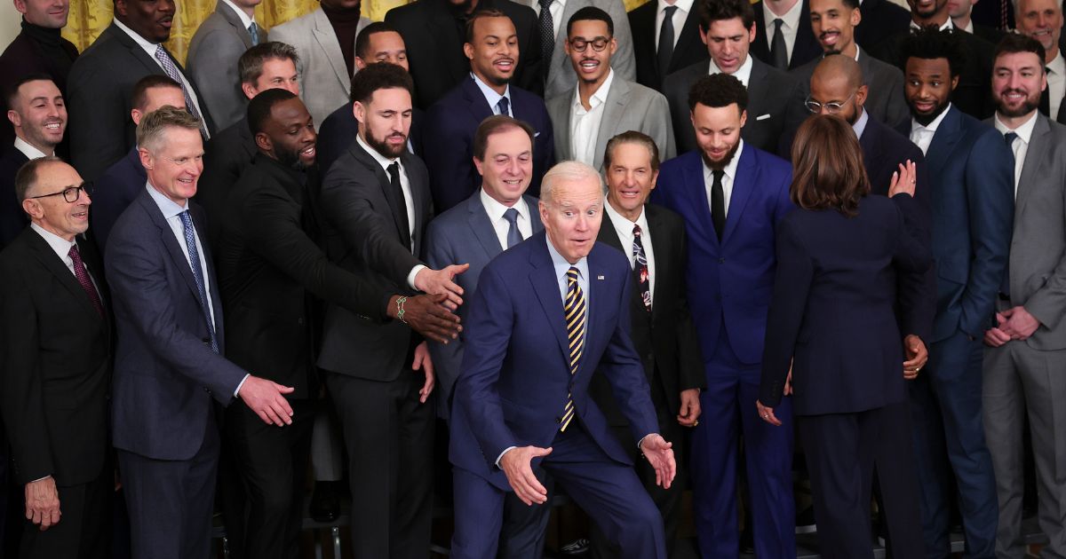 President Joe Biden jokes after posing for a photo with the Golden State Warriors during a ceremony honoring the team in the East Room of the White House Tuesday.