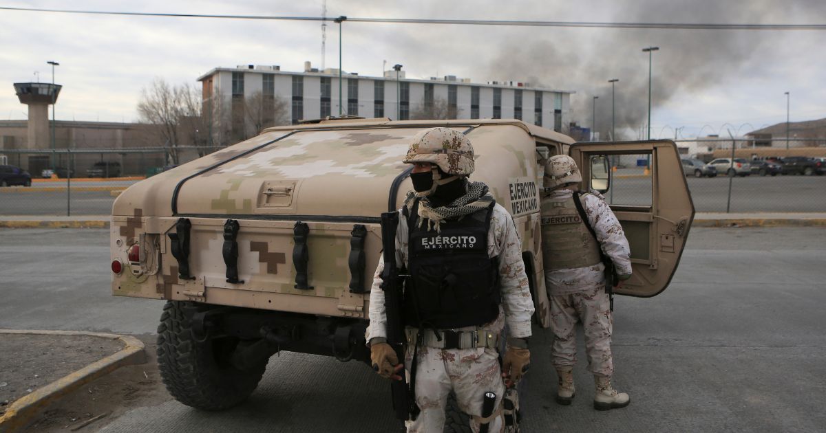 Mexican soldiers stand guard outside a state prison in Ciudad Juarez, Mexico, after violence broke out early Sunday.