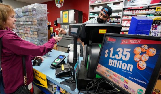 A Mega Millions sign displays the estimated jackpot of $1.35 billion as a customer purchases a Mega Millions ticket at the Cranberry Super Mini Mart in Cranberry, Pennsylvania, on Thursday.