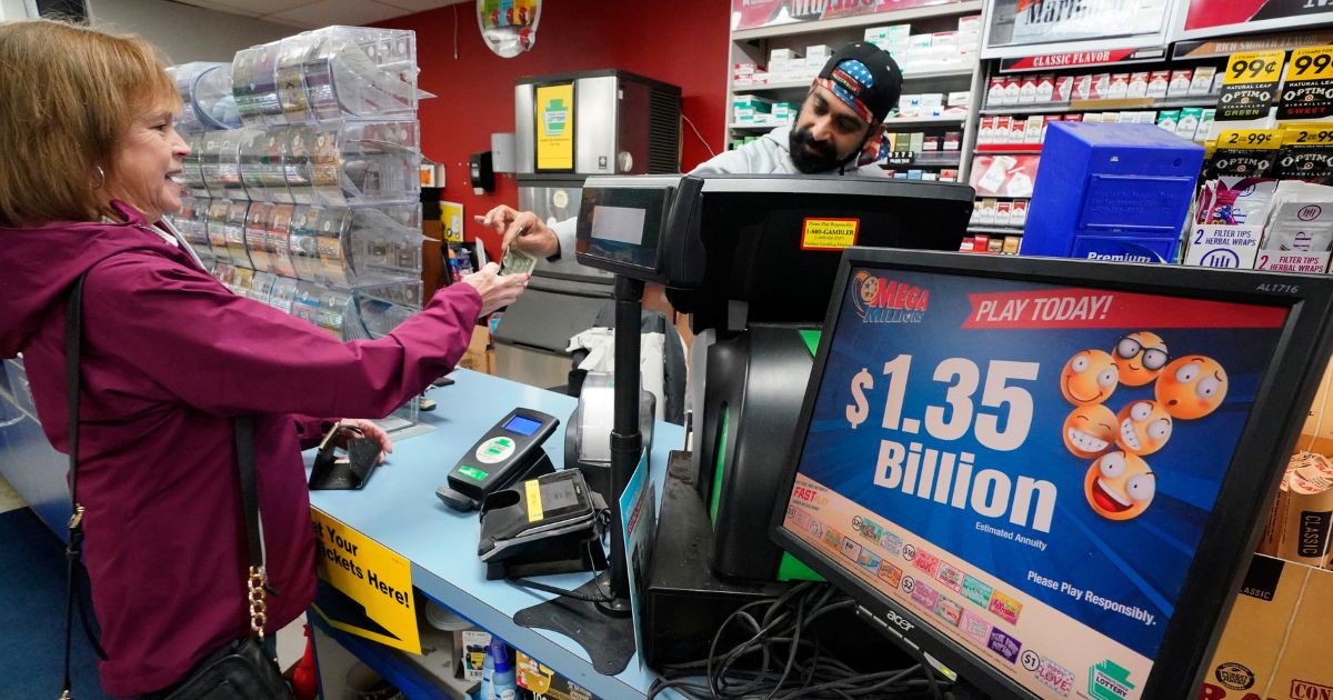 A Mega Millions sign displays the estimated jackpot of $1.35 billion as a customer purchases a Mega Millions ticket at the Cranberry Super Mini Mart in Cranberry, Pennsylvania, on Thursday.