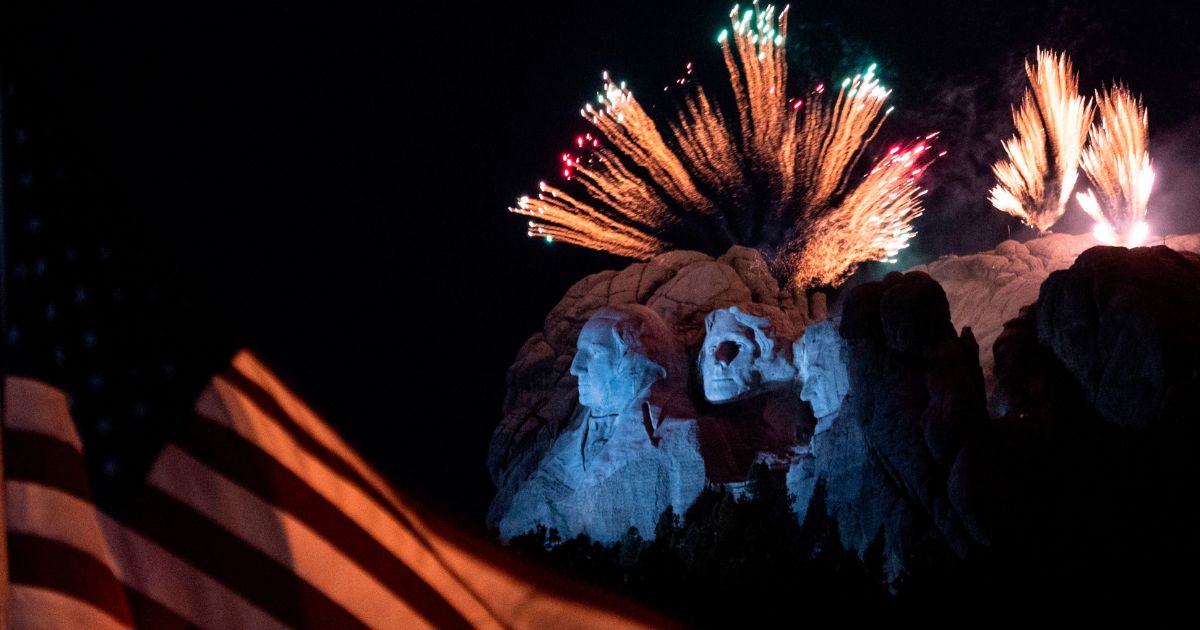 A U.S. flag flies in the forefront while fireworks are set off over Mount Rushmore National Monument in Keystone, South Dakota, on July 3, 2020.