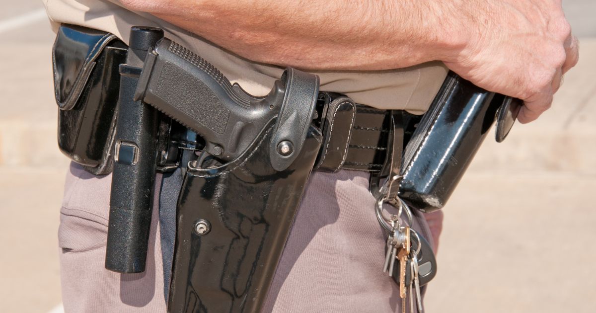 A stock photo shows a sheriff's deputy's black patent leather duty belt with holsters and clips.