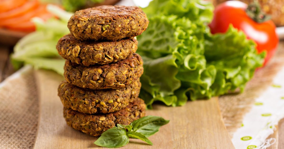 A stock photo shows vegan patties with lentils and pistachios stacked on a cutting board.