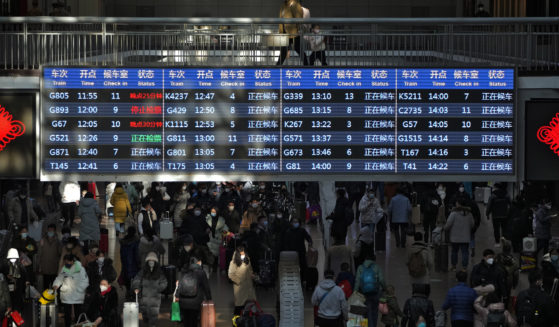 Travelers walk under a train departure board in the West Railway Station of Beijing China, on Sunday.