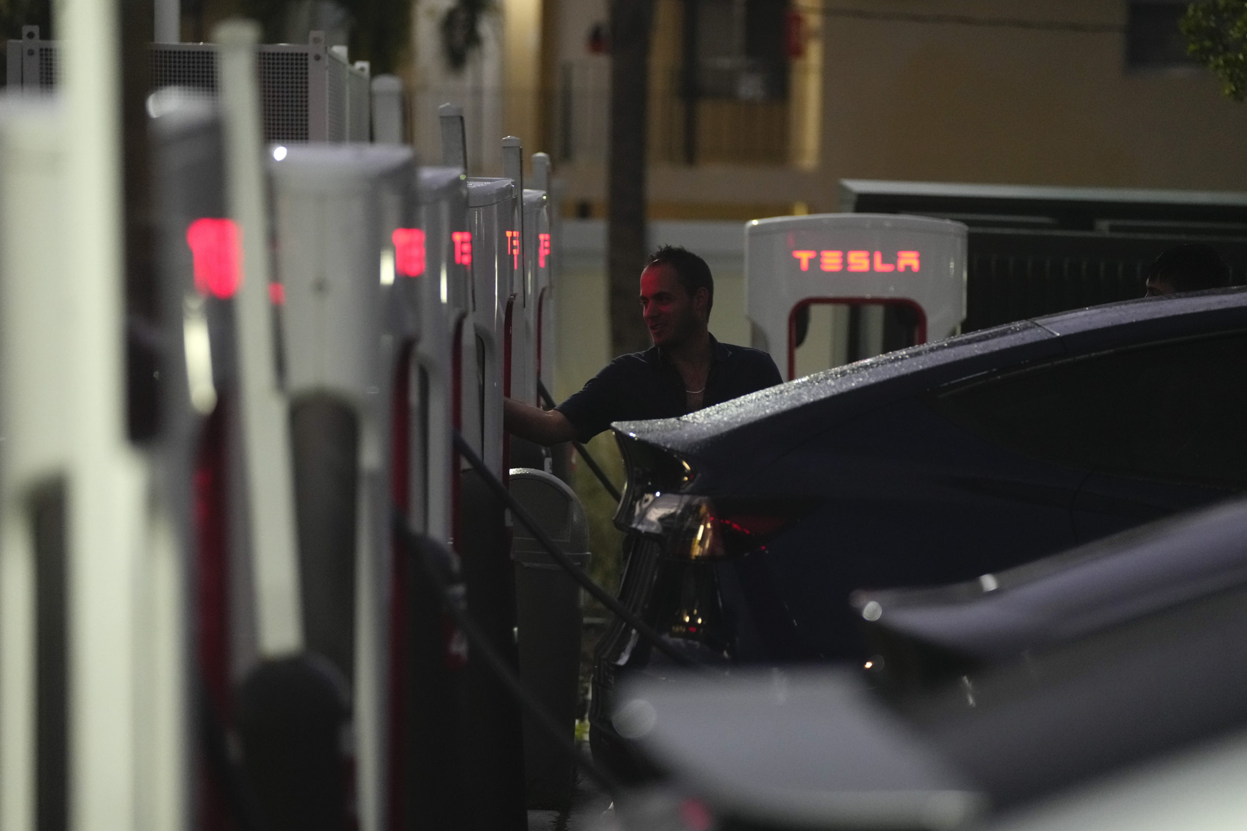 A driver charges his Tesla at a Tesla Supercharger station in Miami, Florida, on Nov. 16.