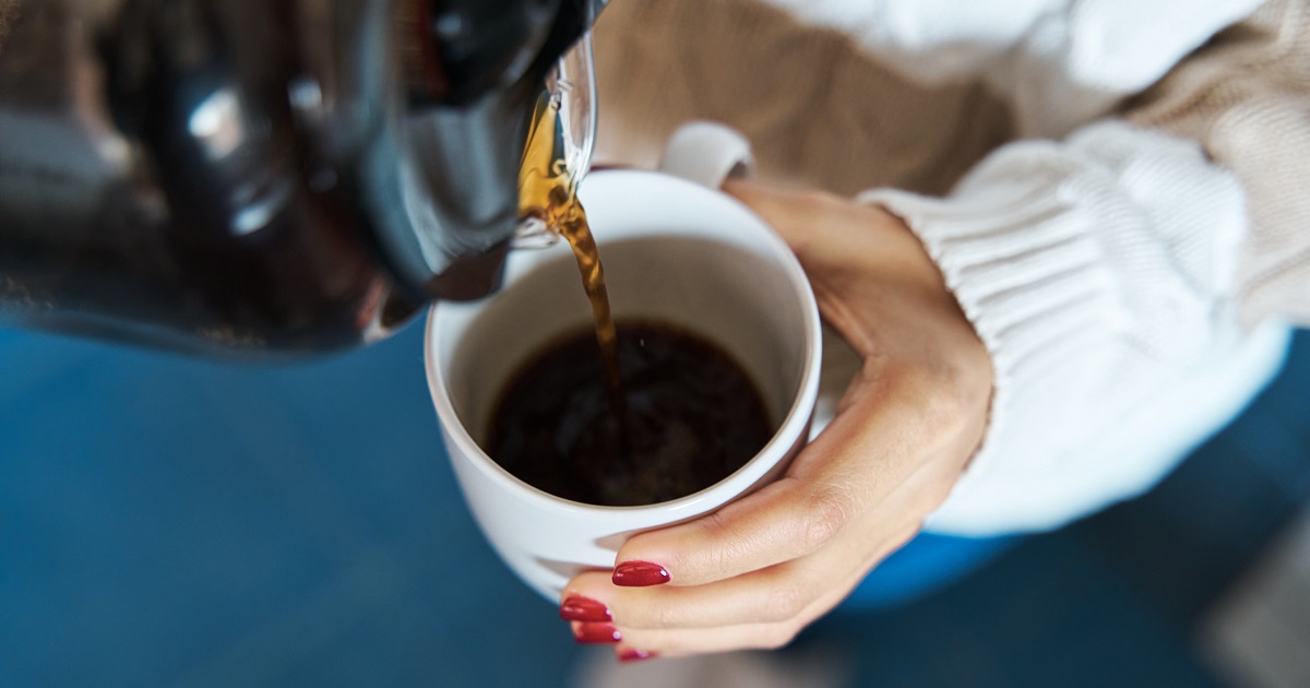 A woman pours herself a cup of coffee.