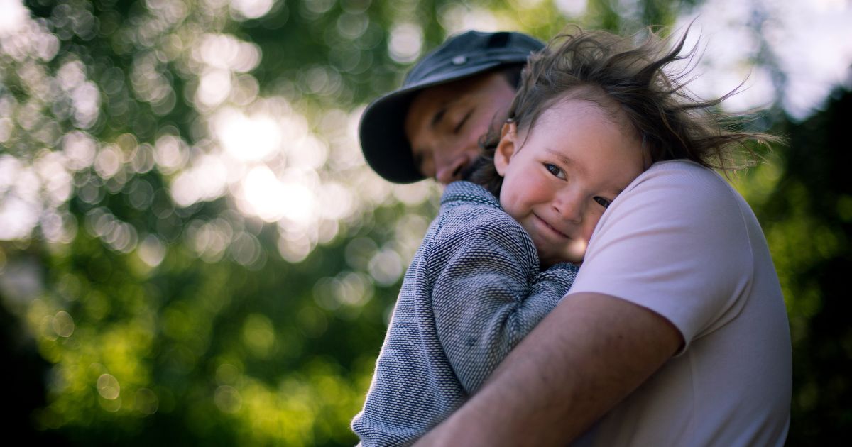 A father holds his son in the above stock image.