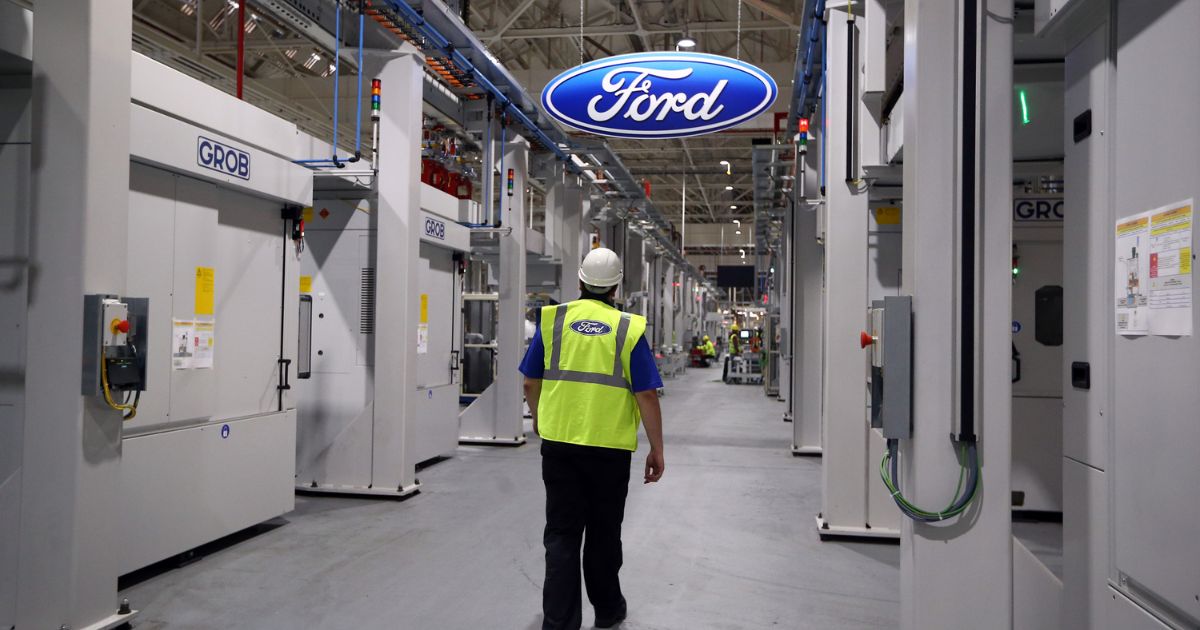 An employee walks past a Ford logo in the yet-to-be-completed engine production line at a Ford factory on Jan. 13, 2015, in Dagenham, England.