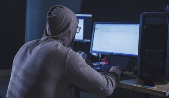 A hacker is seen at a computer.