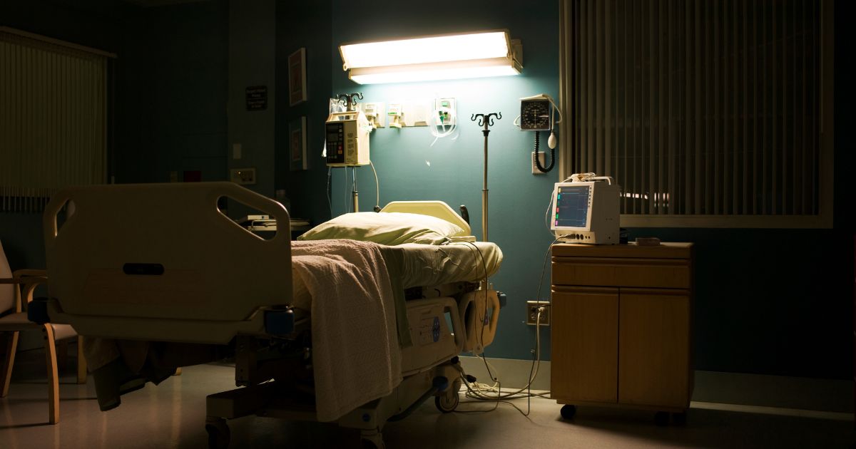 This stock photo depicts an empty hospital bed in a darkened room.