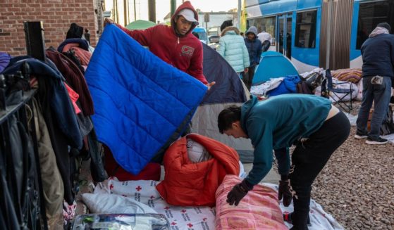 Immigrants pack up blankets after sleeping outside a migrant shelter on January 8, 2023 in El Paso, Texas.